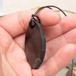 The pendant made of natural black stone has unpolished ends