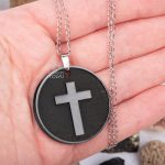 A black stone pendant with a cross engraved on the hand
