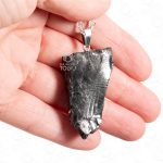 Triangular dark mineral pendant displayed on stainless steel chain in palm